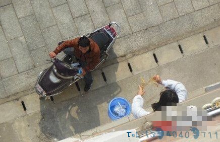 (女生正用桶子将外卖提进公寓)