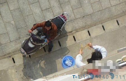 女生正用桶子将外卖提进公寓